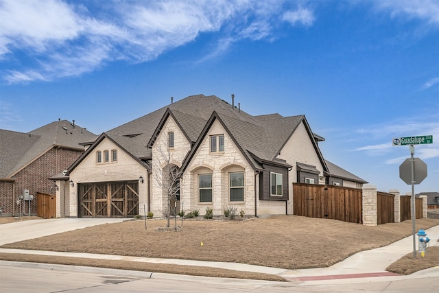 view of front of home featuring a garage, stone siding, fence, and driveway