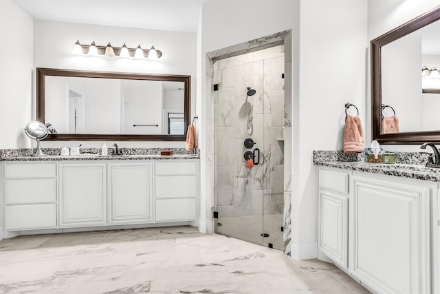 full bath with a stall shower, marble finish floor, two vanities, and a sink