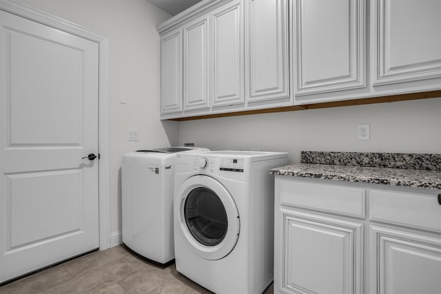 laundry room featuring cabinet space, light tile patterned floors, and washing machine and clothes dryer