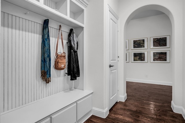 mudroom with arched walkways, dark wood-style flooring, and baseboards