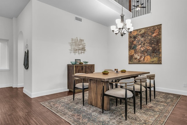 dining area with arched walkways, a notable chandelier, wood finished floors, visible vents, and baseboards