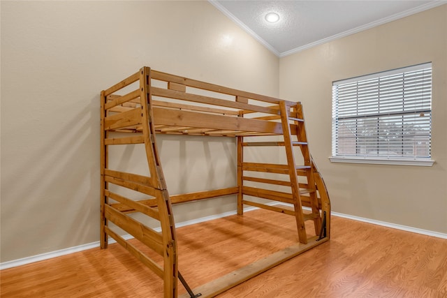 bedroom with baseboards, wood finished floors, and crown molding