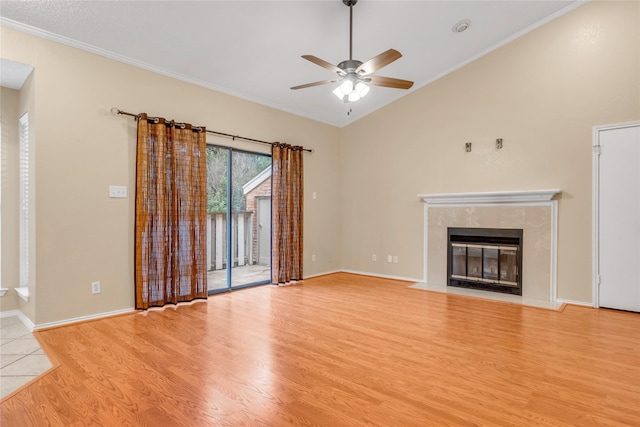 unfurnished living room featuring ornamental molding, a high end fireplace, vaulted ceiling, ceiling fan, and light wood-type flooring