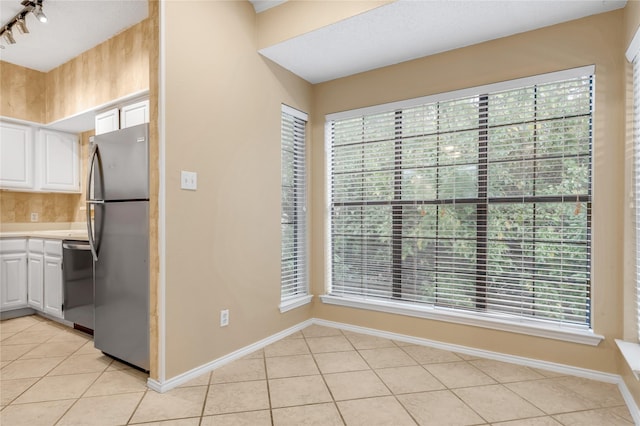 kitchen with light tile patterned floors, stainless steel appliances, light countertops, white cabinetry, and baseboards