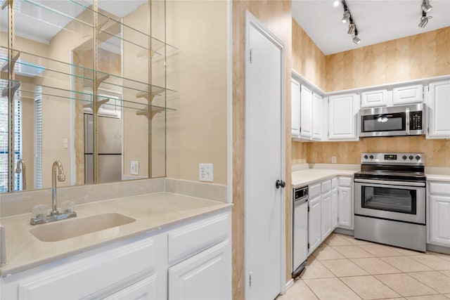 kitchen featuring light tile patterned floors, stainless steel appliances, light countertops, white cabinetry, and a sink