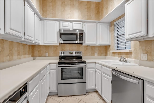 kitchen with appliances with stainless steel finishes, a sink, and white cabinetry