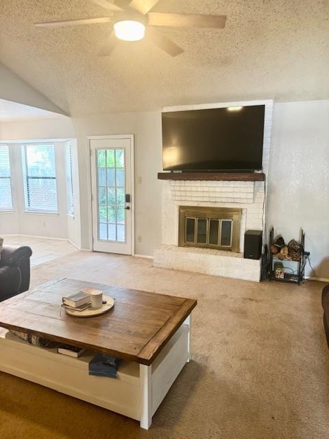 829 Lake Crest Pkwy, Azle, TX 76020 - living room featuring a textured ceiling, a ceiling fan, a brick fireplace, carpet flooring, and vaulted ceiling