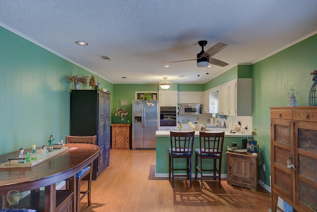 1106 Bryan St, Minden, LA 71055 - kitchen featuring stainless steel appliances, a peninsula, visible vents, white cabinets, and light wood-type flooring