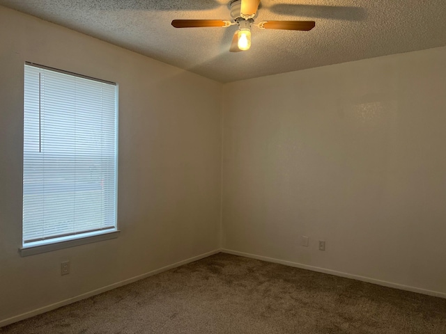 carpeted spare room with ceiling fan, baseboards, and a textured ceiling