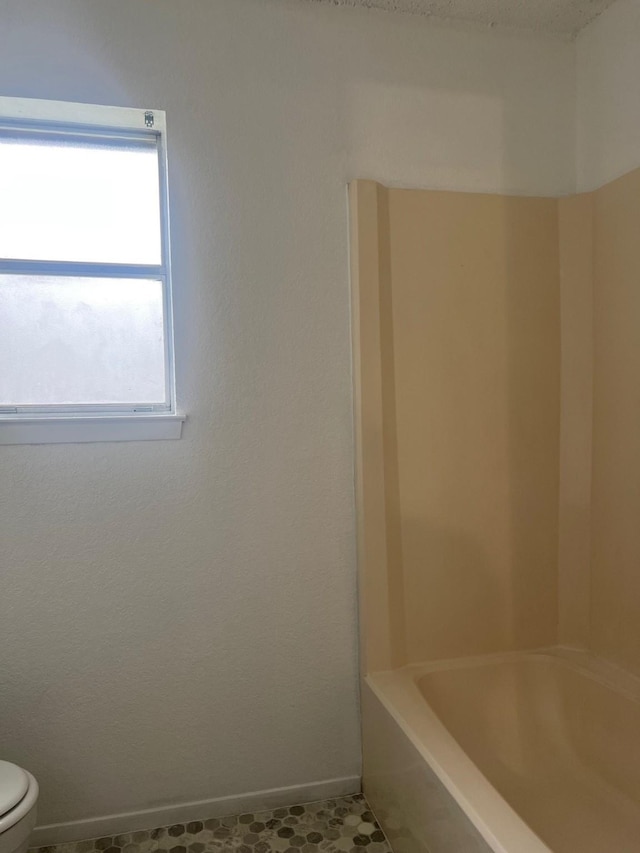 full bathroom featuring toilet and baseboards