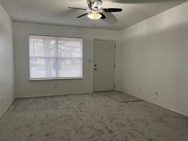 spare room featuring a textured ceiling, carpet floors, ceiling fan, and baseboards