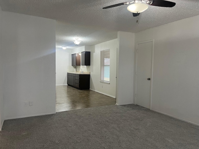 unfurnished room featuring a textured ceiling, ceiling fan, dark carpet, and baseboards