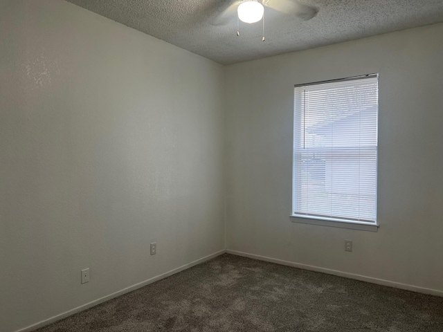 empty room with plenty of natural light, dark carpet, a textured ceiling, and baseboards