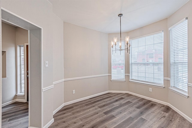 unfurnished room featuring an inviting chandelier, baseboards, and wood finished floors