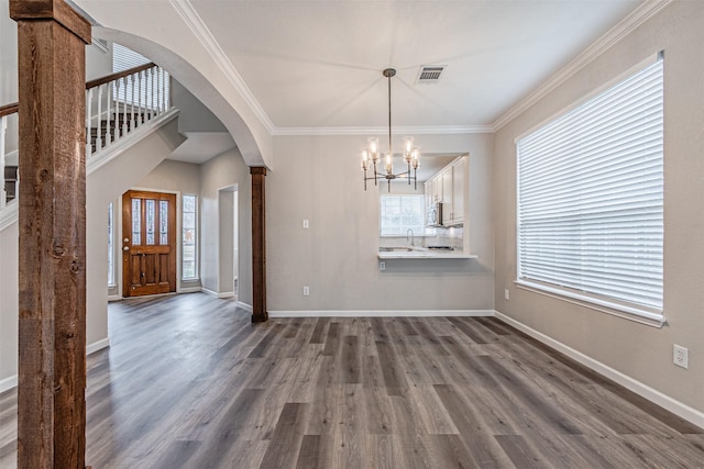 unfurnished dining area featuring baseboards, dark wood finished floors, arched walkways, and ornamental molding