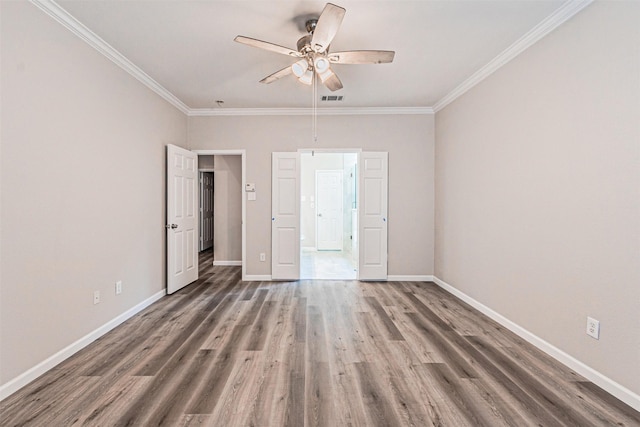 unfurnished room featuring baseboards, visible vents, wood finished floors, and ornamental molding