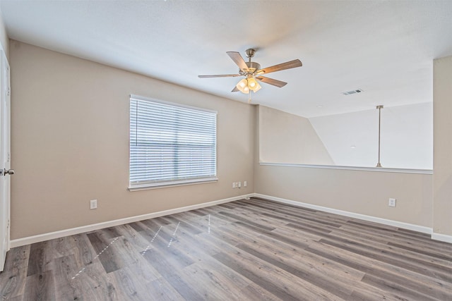 empty room with baseboards, visible vents, ceiling fan, and wood finished floors