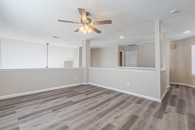 unfurnished room with visible vents, wood finished floors, a ceiling fan, and baseboards