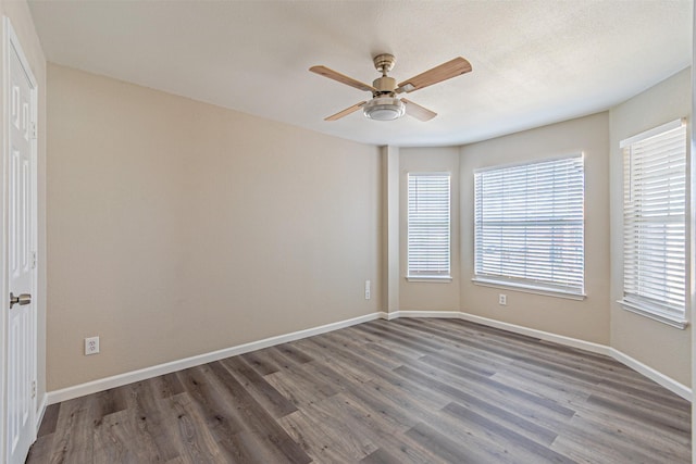 empty room featuring a textured ceiling, wood finished floors, a ceiling fan, and baseboards