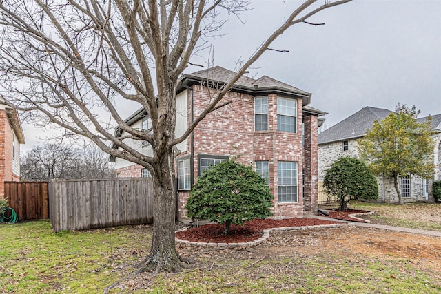 view of home's exterior with brick siding, roof with shingles, and fence