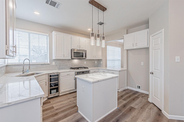 kitchen with stainless steel appliances, visible vents, backsplash, a sink, and beverage cooler