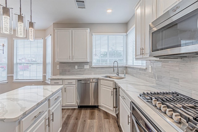 kitchen featuring stainless steel appliances, a sink, visible vents, light wood-style floors, and white cabinets