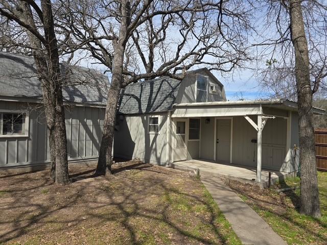 rear view of property with board and batten siding, a patio area, fence, and a gambrel roof