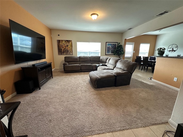 living area featuring baseboards, visible vents, a wealth of natural light, and light colored carpet