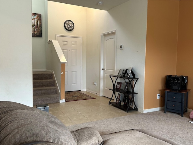 tiled foyer entrance featuring carpet floors, stairs, and baseboards