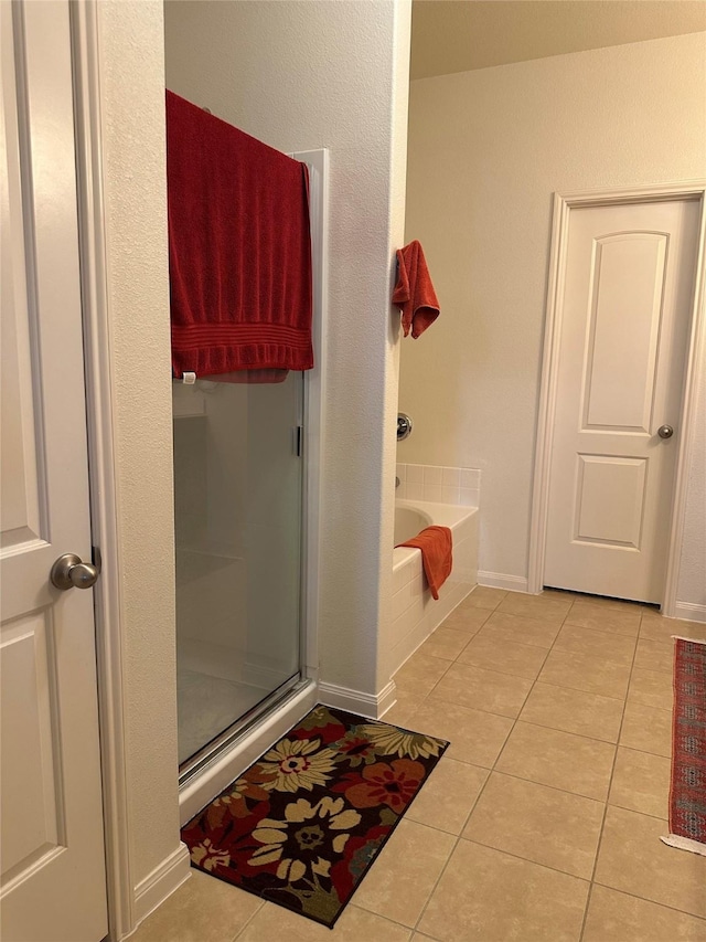 bathroom with baseboards, a shower stall, a bath, and tile patterned floors