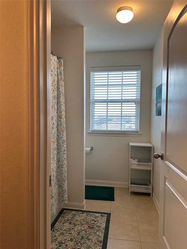 bathroom featuring a shower with shower curtain, baseboards, and tile patterned floors