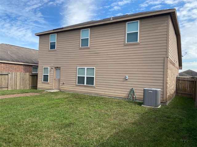 rear view of property featuring a yard, brick siding, a fenced backyard, and central air condition unit