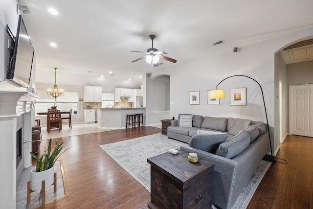 living area with arched walkways, hardwood / wood-style floors, ceiling fan with notable chandelier, and visible vents