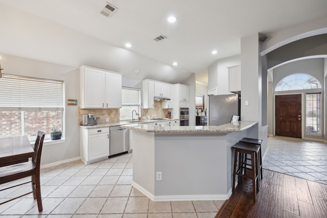 kitchen with tasteful backsplash, visible vents, white cabinets, appliances with stainless steel finishes, and a peninsula