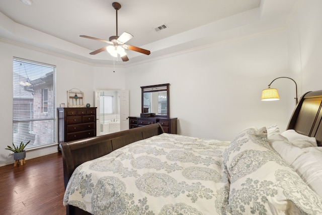 bedroom featuring visible vents, a raised ceiling, a ceiling fan, ornamental molding, and dark wood-style flooring