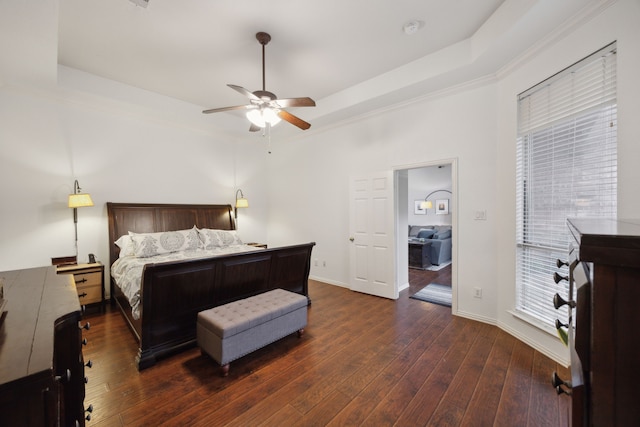 bedroom featuring dark wood-style floors, baseboards, a tray ceiling, and a ceiling fan