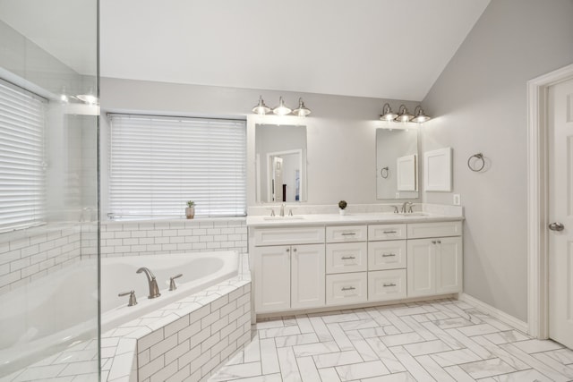 bathroom featuring double vanity, a garden tub, vaulted ceiling, and a sink