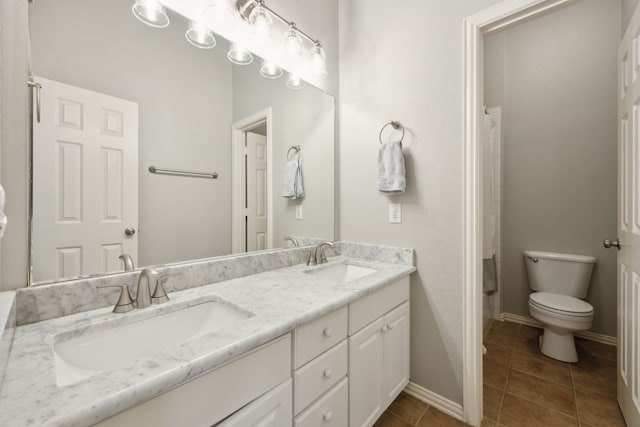 bathroom featuring toilet, double vanity, a sink, and tile patterned floors