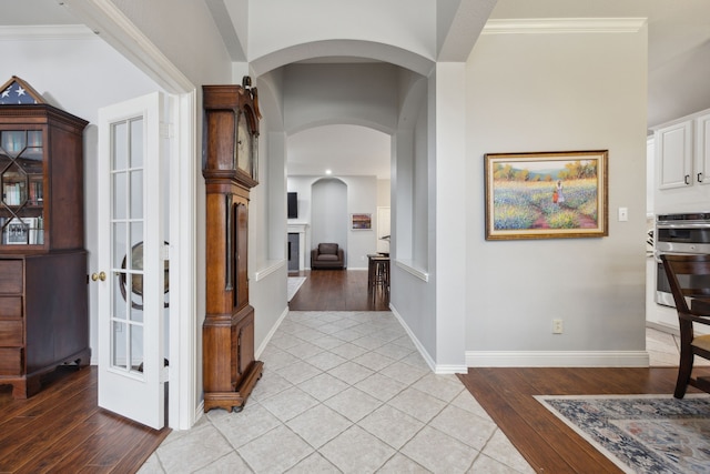 corridor with ornamental molding, light wood-type flooring, and baseboards