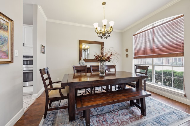 dining room with wood finished floors, crown molding, baseboards, and an inviting chandelier