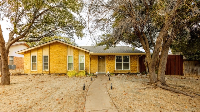 single story home featuring central air condition unit, fence, and brick siding