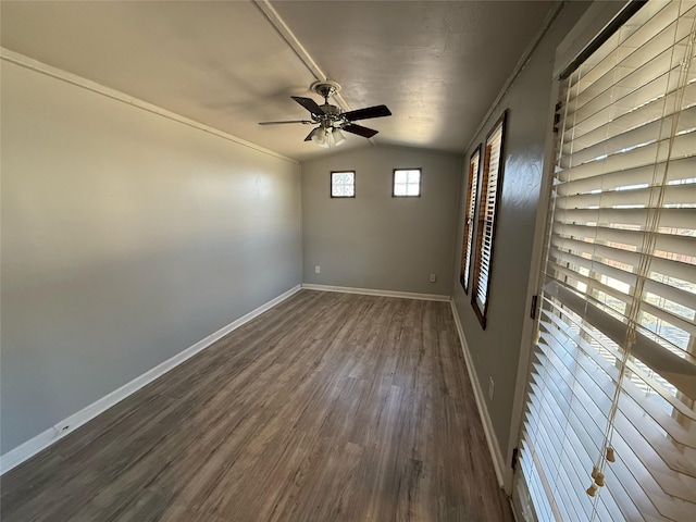 empty room featuring a ceiling fan, vaulted ceiling, dark wood-style floors, and baseboards