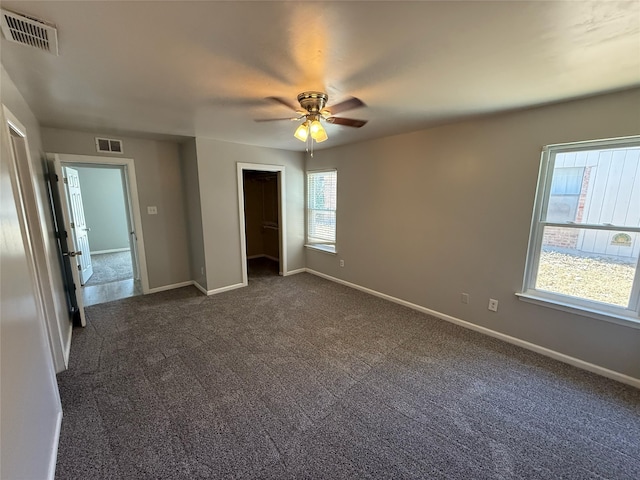 unfurnished bedroom with visible vents, baseboards, and dark carpet