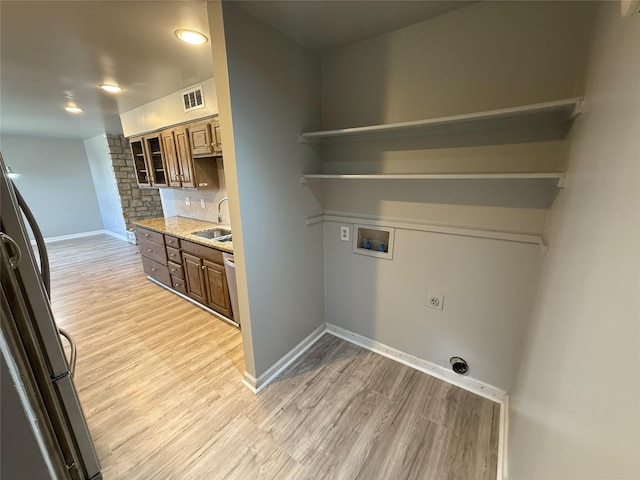 clothes washing area featuring light wood finished floors, visible vents, washer hookup, hookup for an electric dryer, and a sink