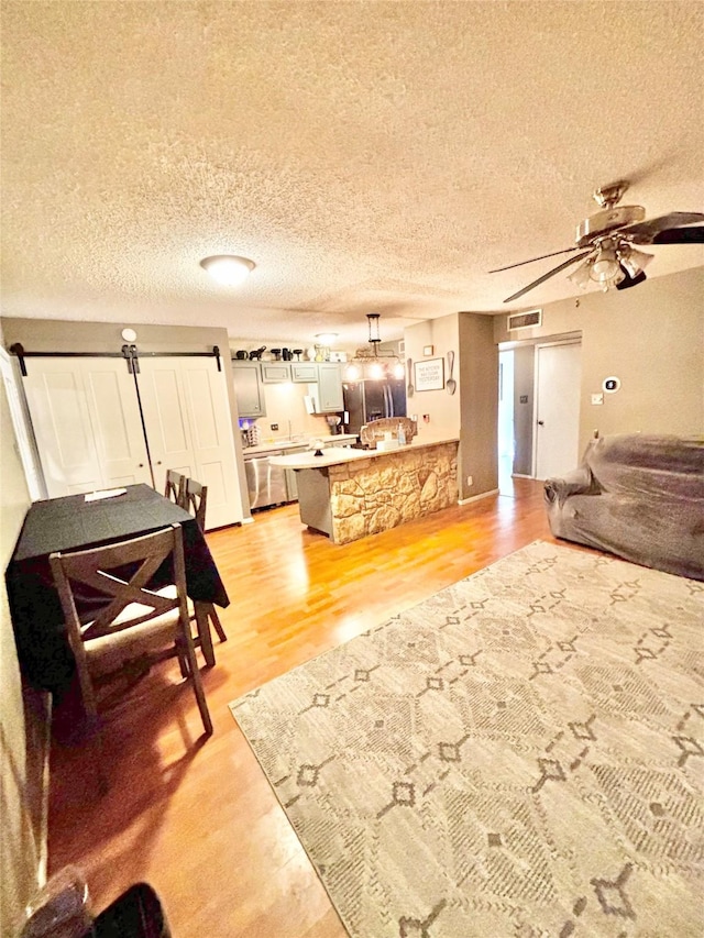 kitchen with open floor plan, a peninsula, a breakfast bar area, and light wood-style floors