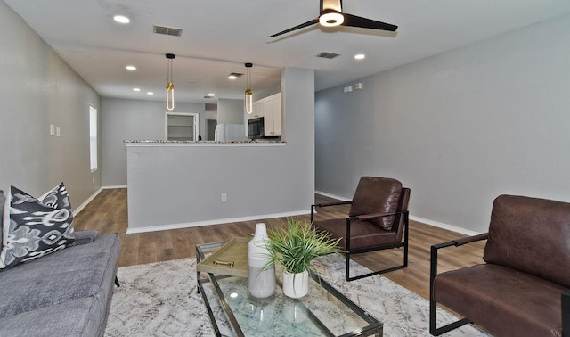 living area with wood finished floors, visible vents, and baseboards