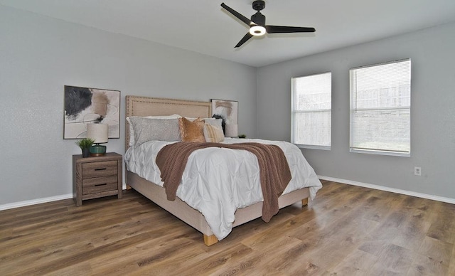 bedroom with a ceiling fan, baseboards, and wood finished floors