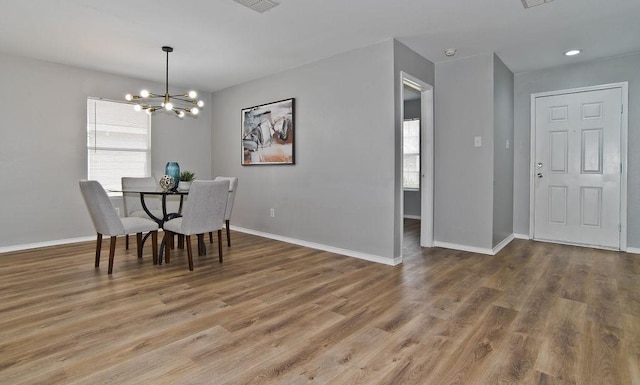 dining space featuring baseboards, an inviting chandelier, wood finished floors, and a healthy amount of sunlight