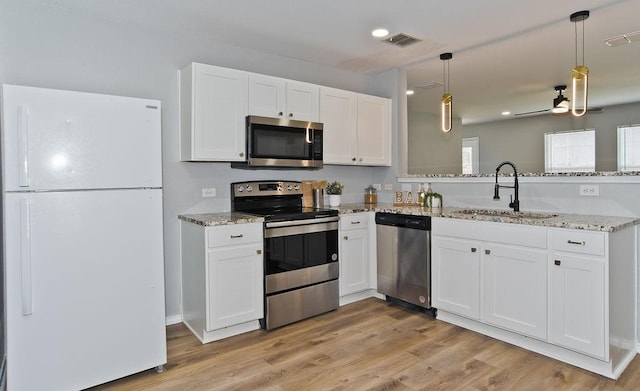 kitchen featuring a peninsula, white cabinetry, appliances with stainless steel finishes, and a sink