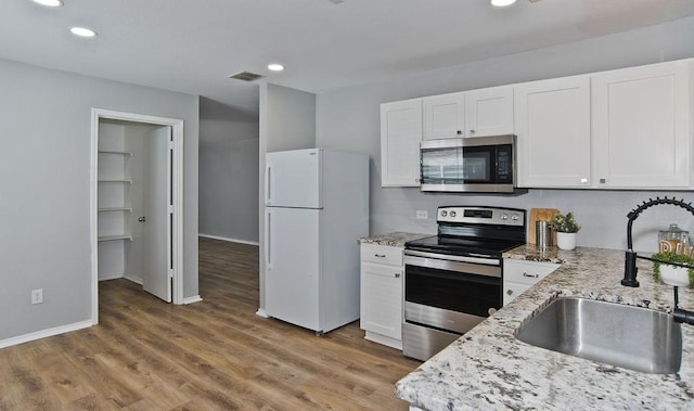 kitchen with light wood-style flooring, white cabinetry, stainless steel appliances, and a sink